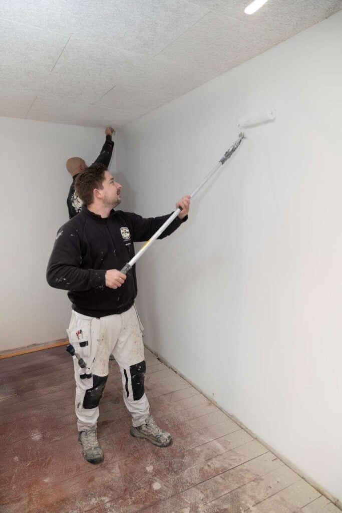 Professionel maler bruger rulle til maling af højt loft