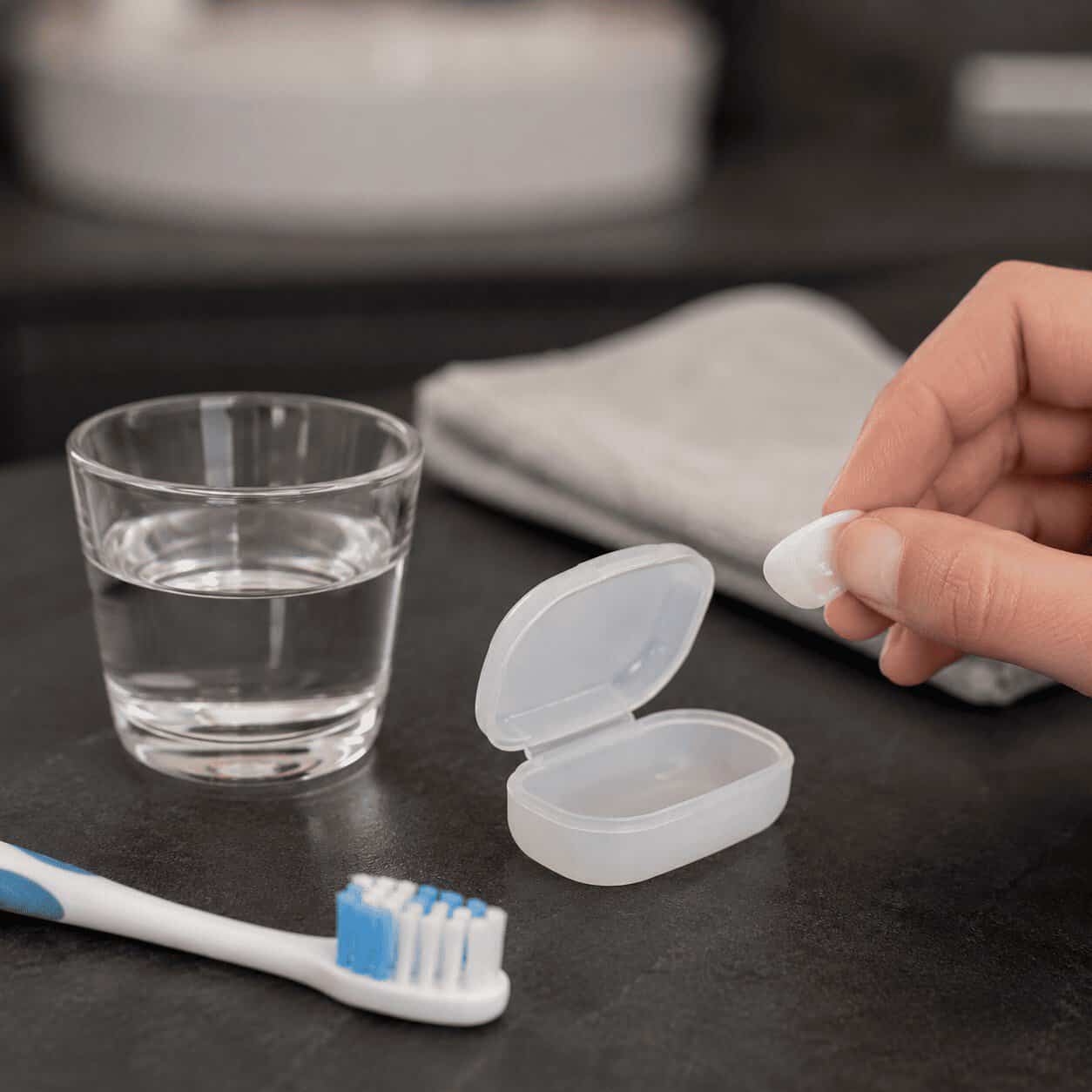 Faccetta dentale staccata conservata in una scatolina pulita prima della visita.