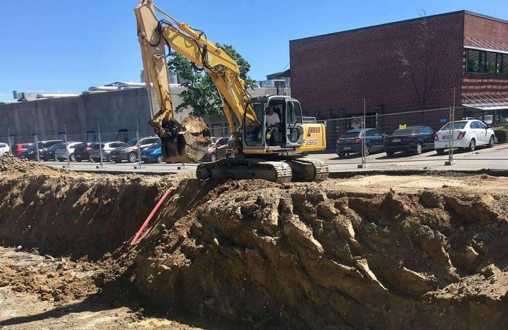Gravemaskine arbejder på byggeplads med jordbrydning og udgravning.