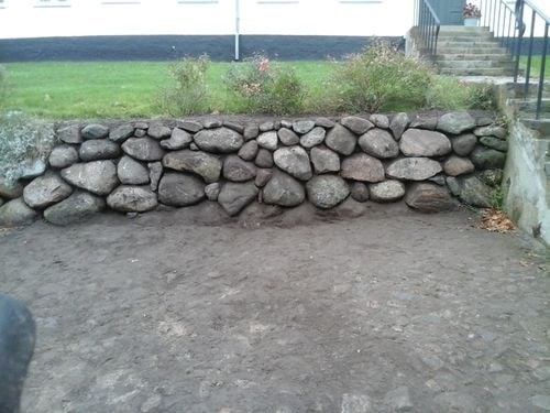 Stenmur lavet af store, runde sten til haveafgrænsning.