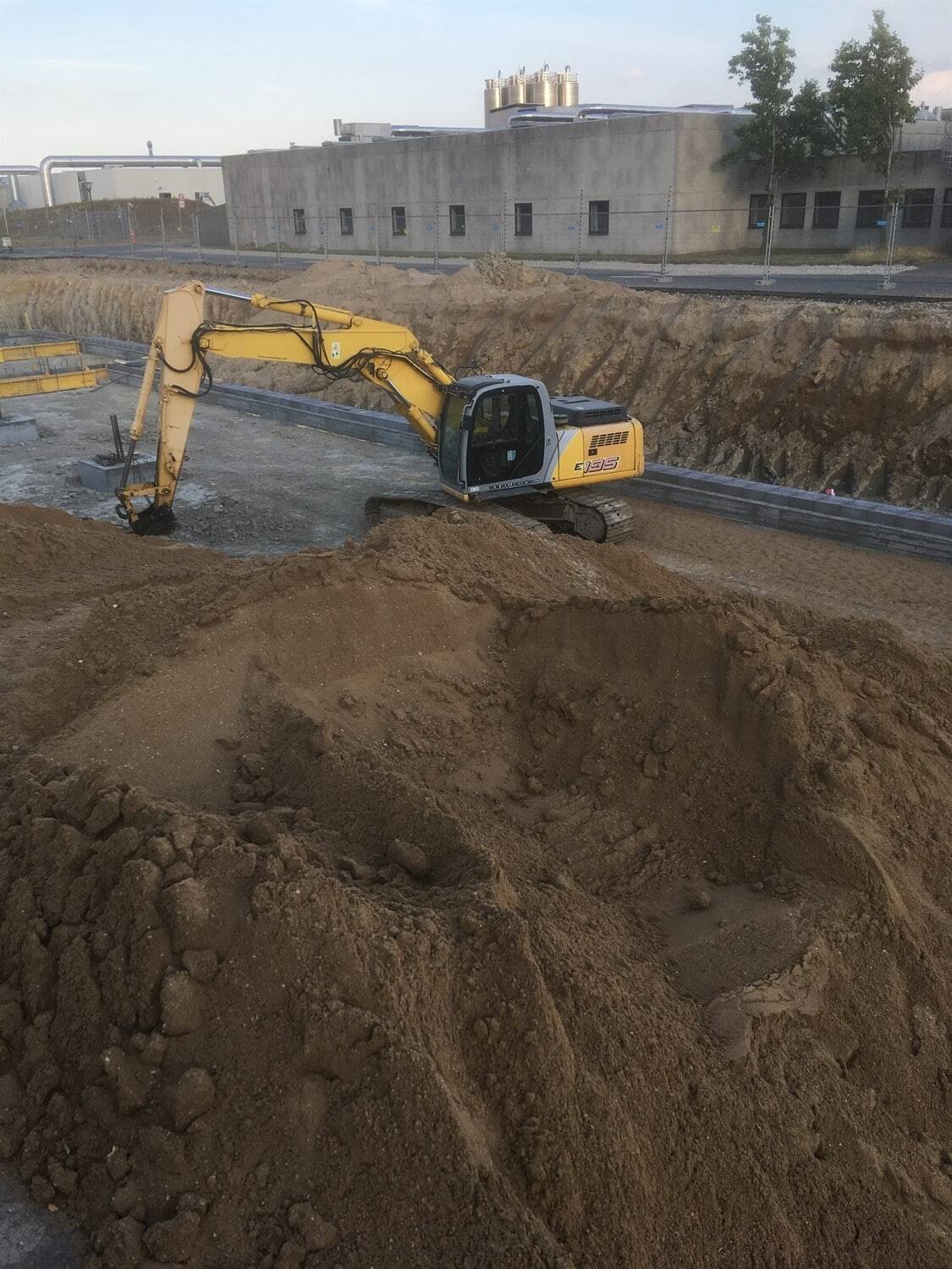 Gravemaskine arbejder på byggeplads til jordarbejde og fundamentforberedelse.