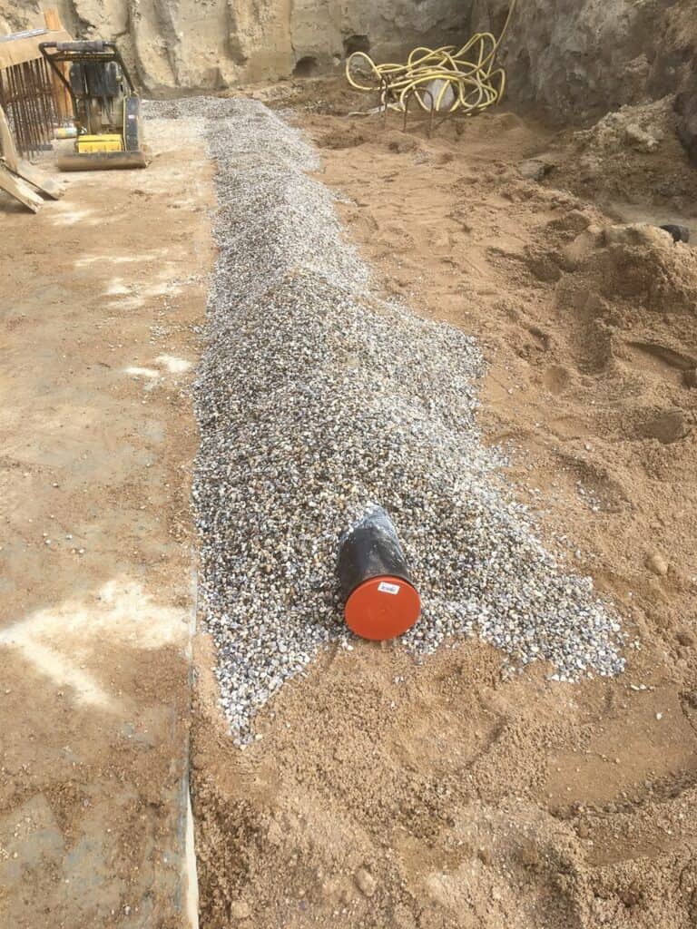 Vejbygning med grus og rør til infrastruktur.