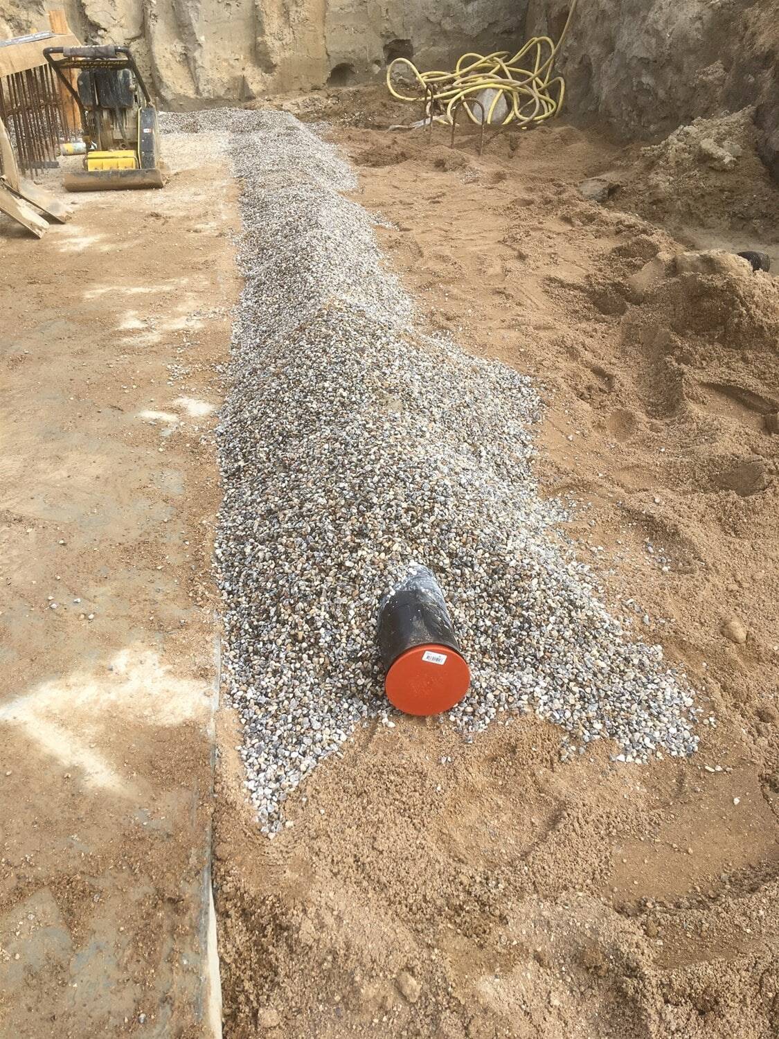 Vejbygning med grus og rør til infrastruktur.