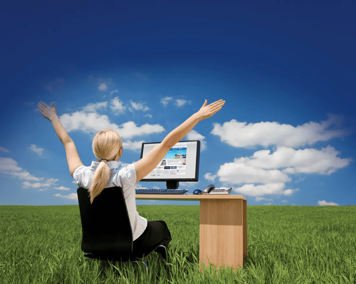 Woman sitting at her desk with a computer in the middle of a field
