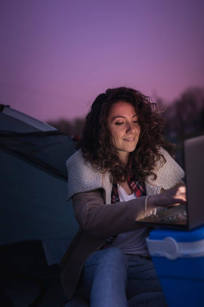 Woman sitting outside at night working on her computer.