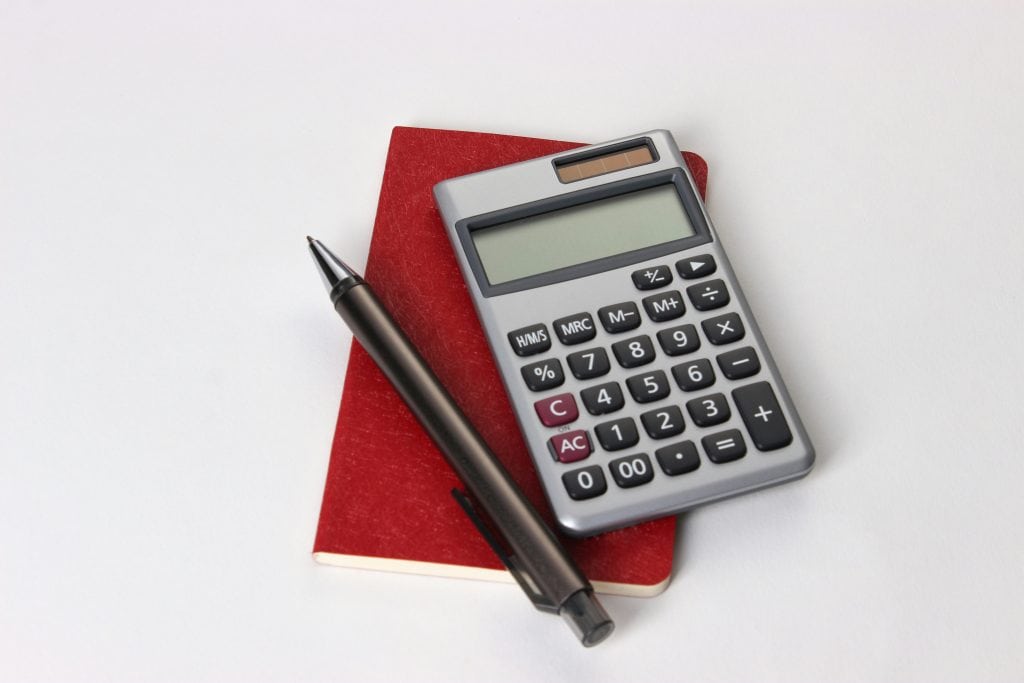 Red notebook with a calculator and pen on top, representing LLC ownership percentage calculations and planning.