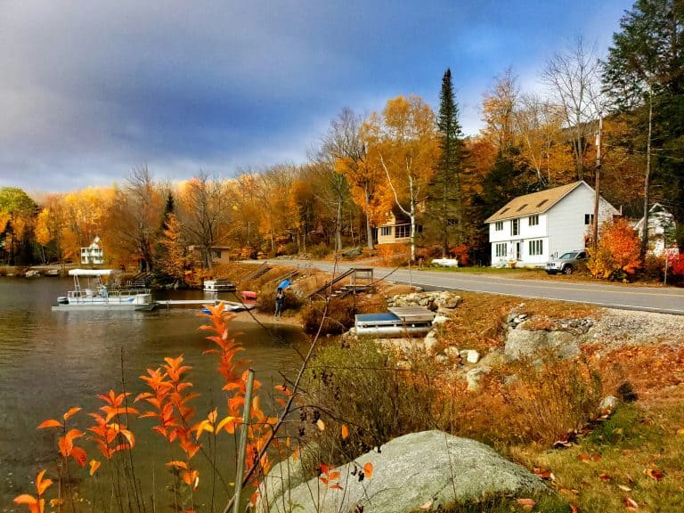 Serene lakeside scene with a white house and picket fence, representing the tranquility of conducting a New Hampshire business entity search.