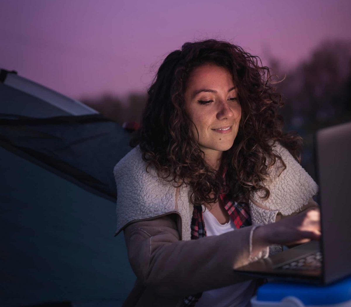 Woman sitting outside at night working on her computer.