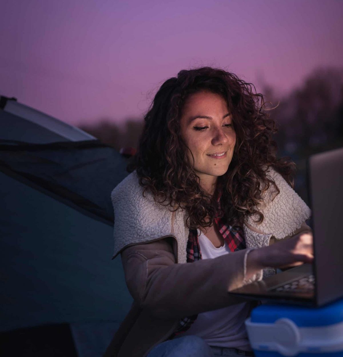 Woman sitting outside at night working on her computer.