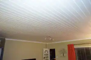 Smooth white drywall ceiling with modern lighting fixtures in a living room.