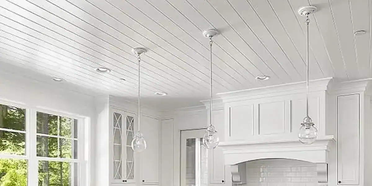 Ceiling and drywall ceiling installation in a modern kitchen with white cabinetry and large windows.