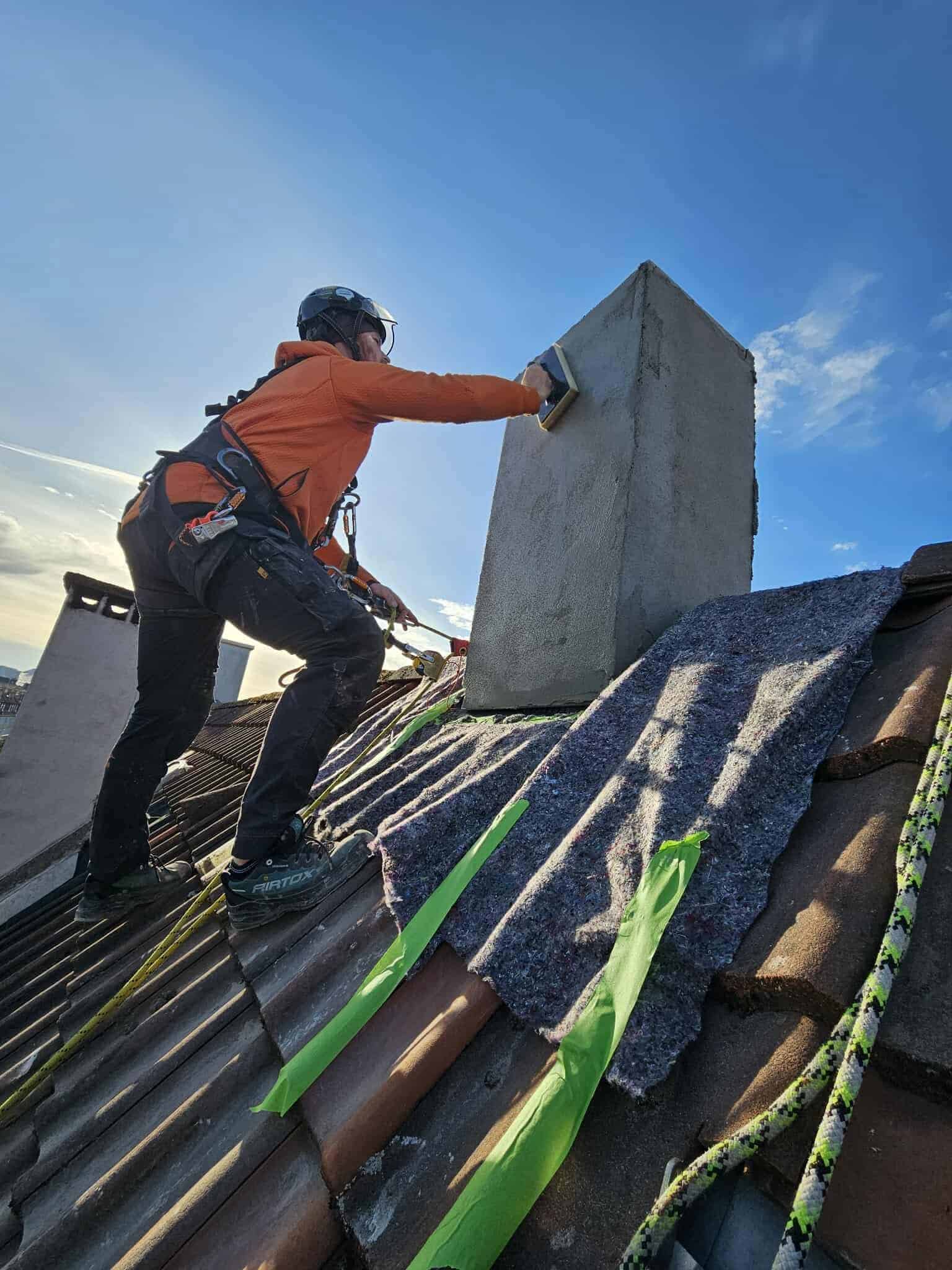 Håndværker står på tagkant ved skorsten
