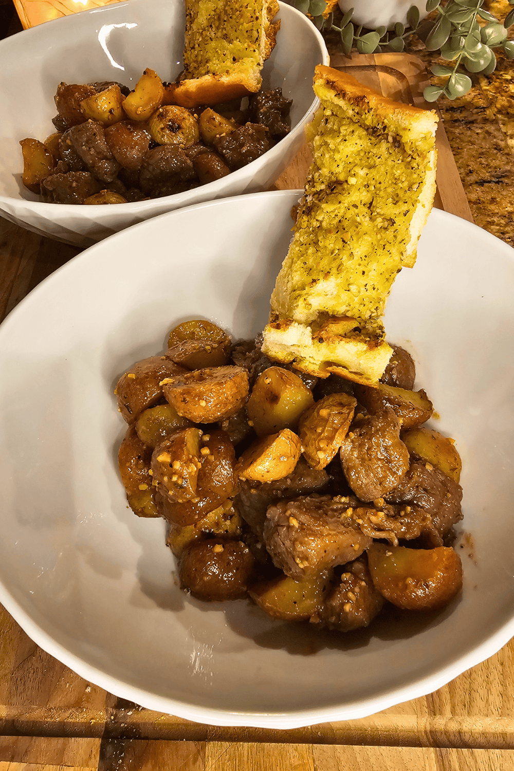 Juicy garlic butter steak with roasted potatoes in a white bowl.