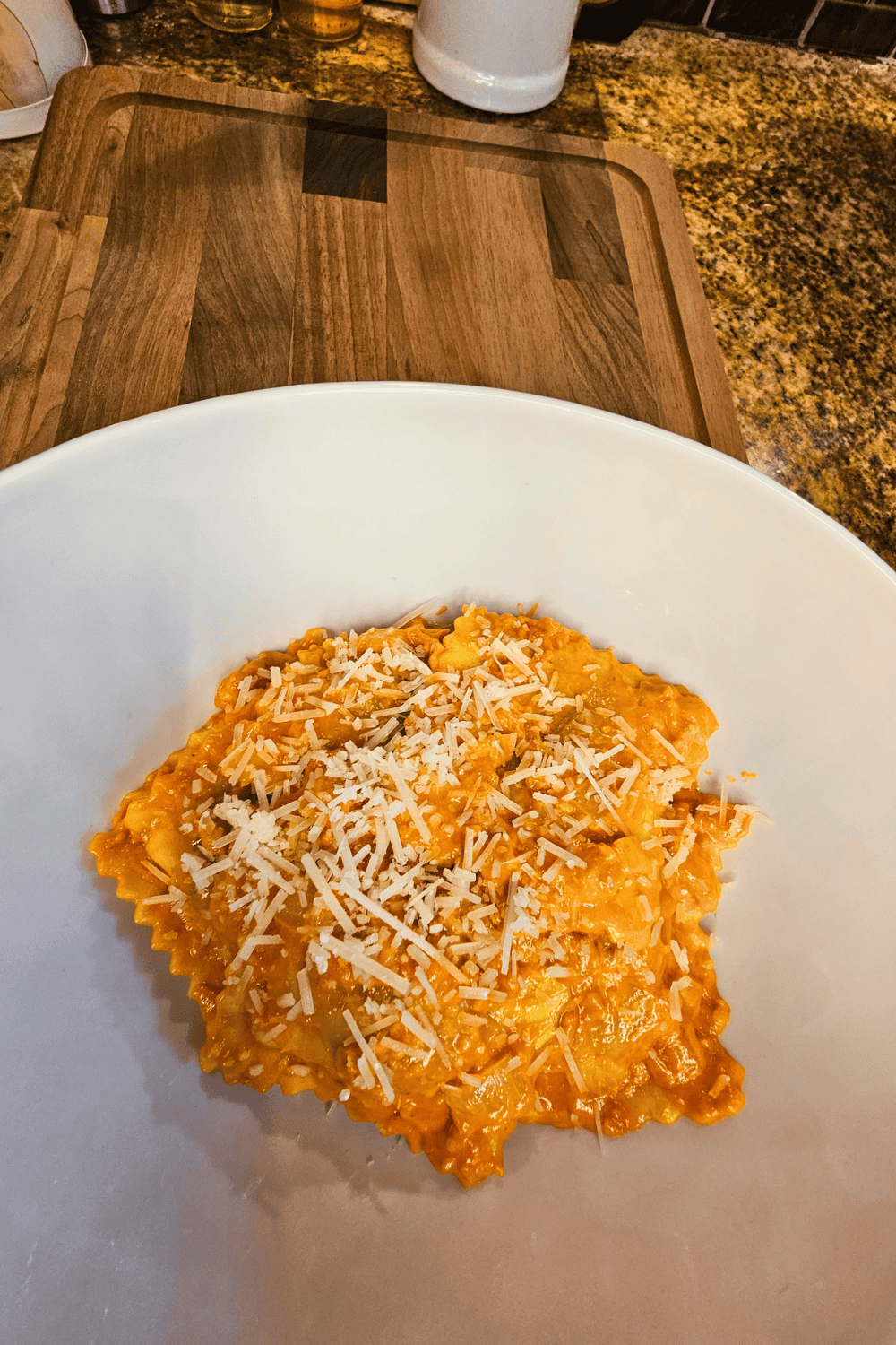 Delicious ravioli topped with creamy pink sauce and shredded cheese, served in a cozy bowl for a com.