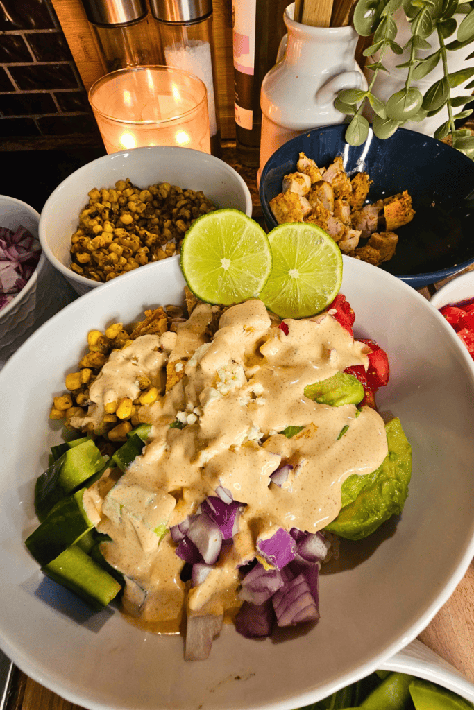 Healthy chicken and veggie bowl with creamy sauce, cucumbers, and lime garnish.