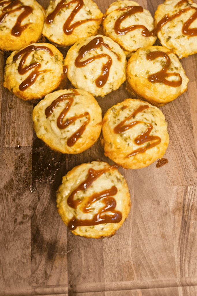 Delicious Sloppy Joe Muffins drizzled with barbeque sauce on a wooden surface.