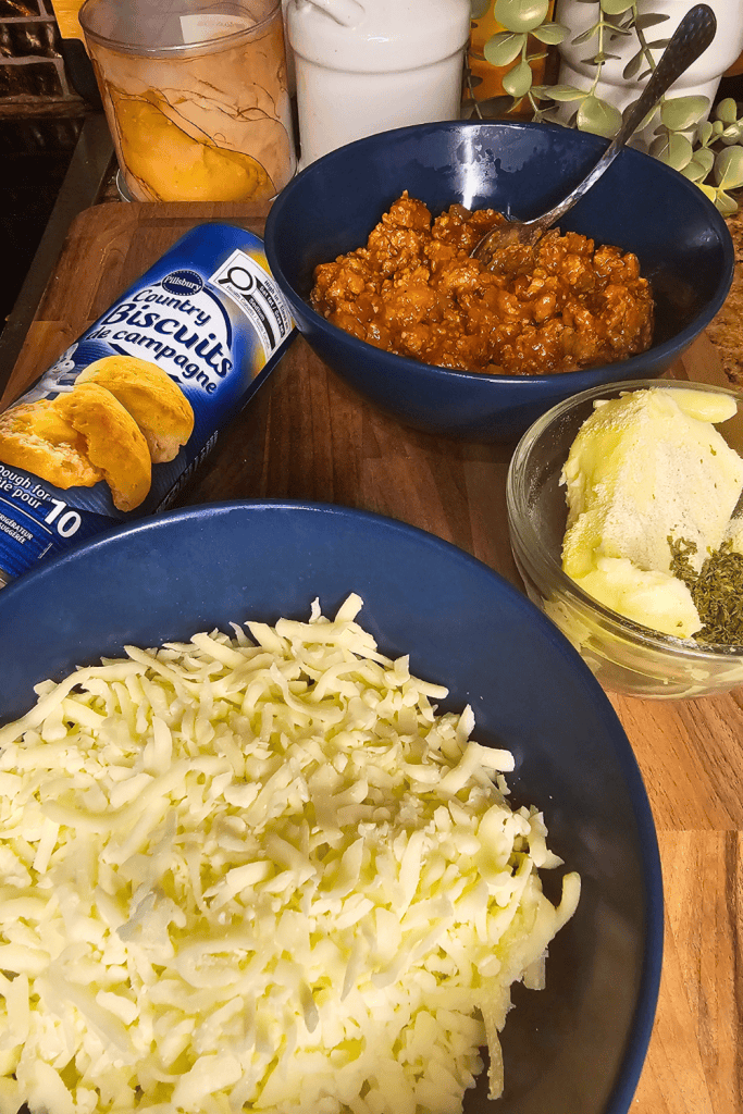 Hearty sloppy joe mixture with shredded cheese and biscuits ready to be made into muffins.