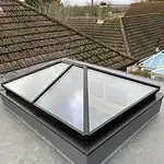 Bright roof skylight with black frame on flat roof for natural light in home.