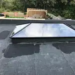 Skylight window installation on flat roof for natural light, weatherproofing, and energy efficiency.