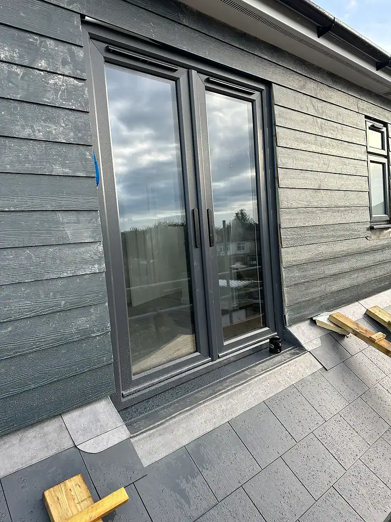 Aluminium sliding patio doors with grey frame on modern exterior wall.