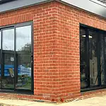 Modern black-framed sliding glass doors installed on a brick building for enhanced safety and insulation.