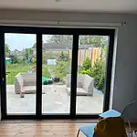 Modern black framed sliding glass patio door, leading to garden. Custom aluminium window installation by CP Glazing Ltd.
