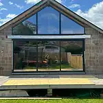 Modern conservatory with large bi-fold doors and glass roof, perfect for stylish home extensions.