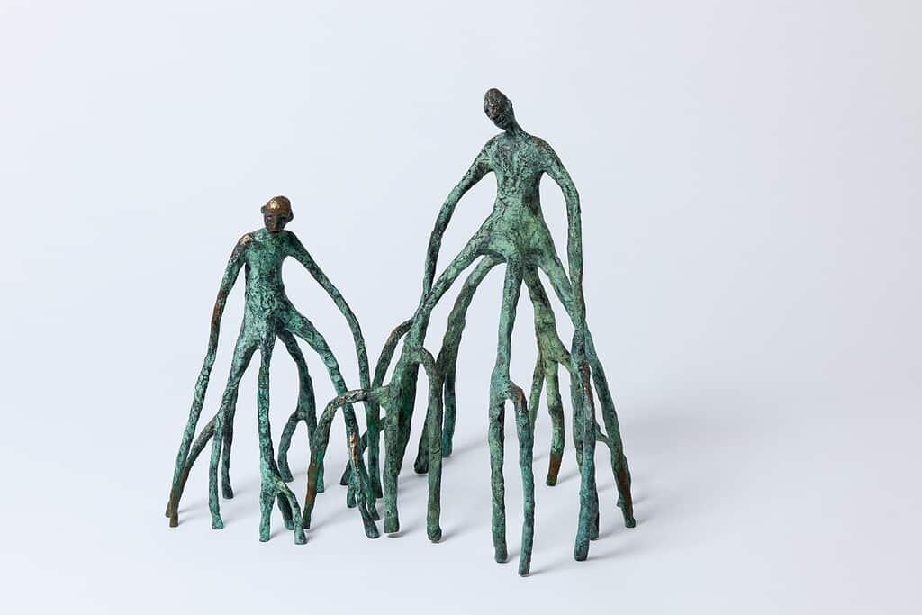 Bronze kunstskulptur af to mennesker med lange ben og arme.