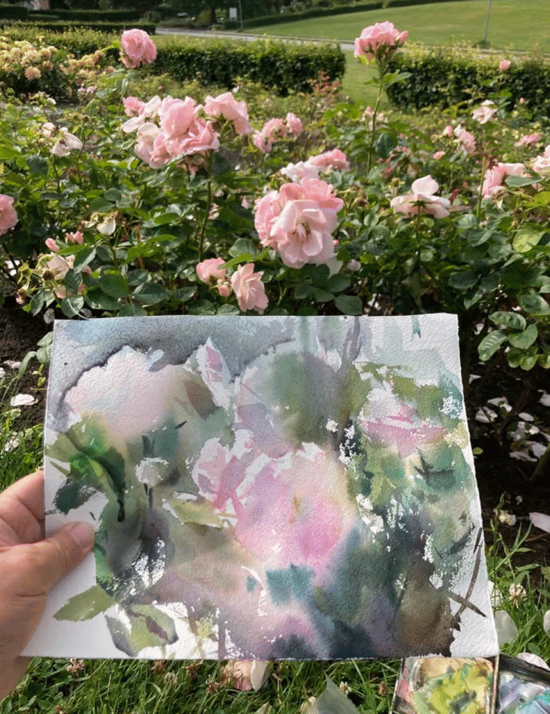 Lila roser i Dronninglund Kunstcenter's have med kunstnerisk maleri i forgrunden.