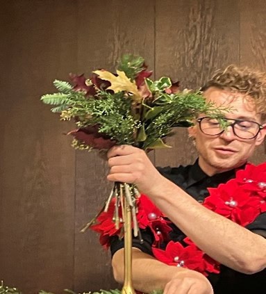 Farverig blomsterbuket med julepynt og mand, kunstcenter, kreativitet og kunsthåndværk, Dronninglund Kunstcenter, dansk kunstoplevelse.