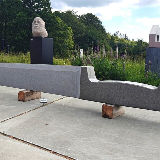 Moderne skulptur i Dronninglund Kunstcenter med grønne omgivelser.