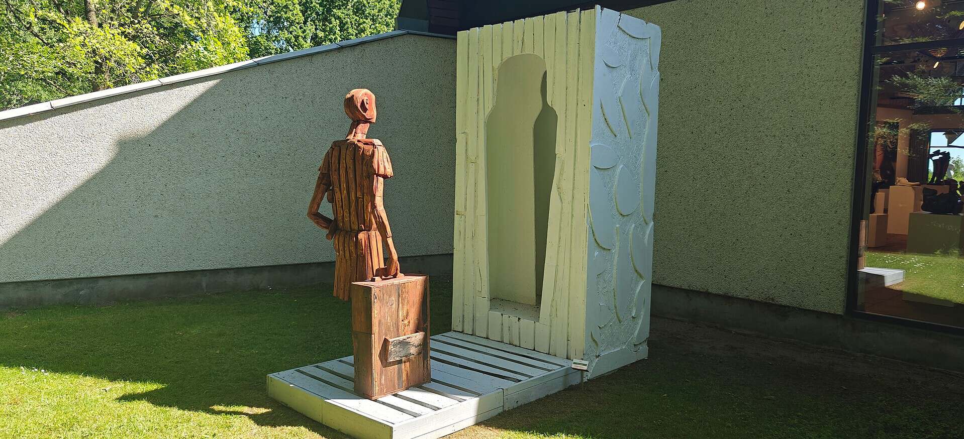 Kunstinstallation med figur foran en stor, kunstnerisk dør ved Dronninglund Kunstcenter.