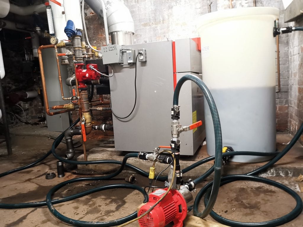 Ecowaterlab on-site chemical cleaning setup with dosing pump, mixing tank, and boiler system during industrial maintenance service.