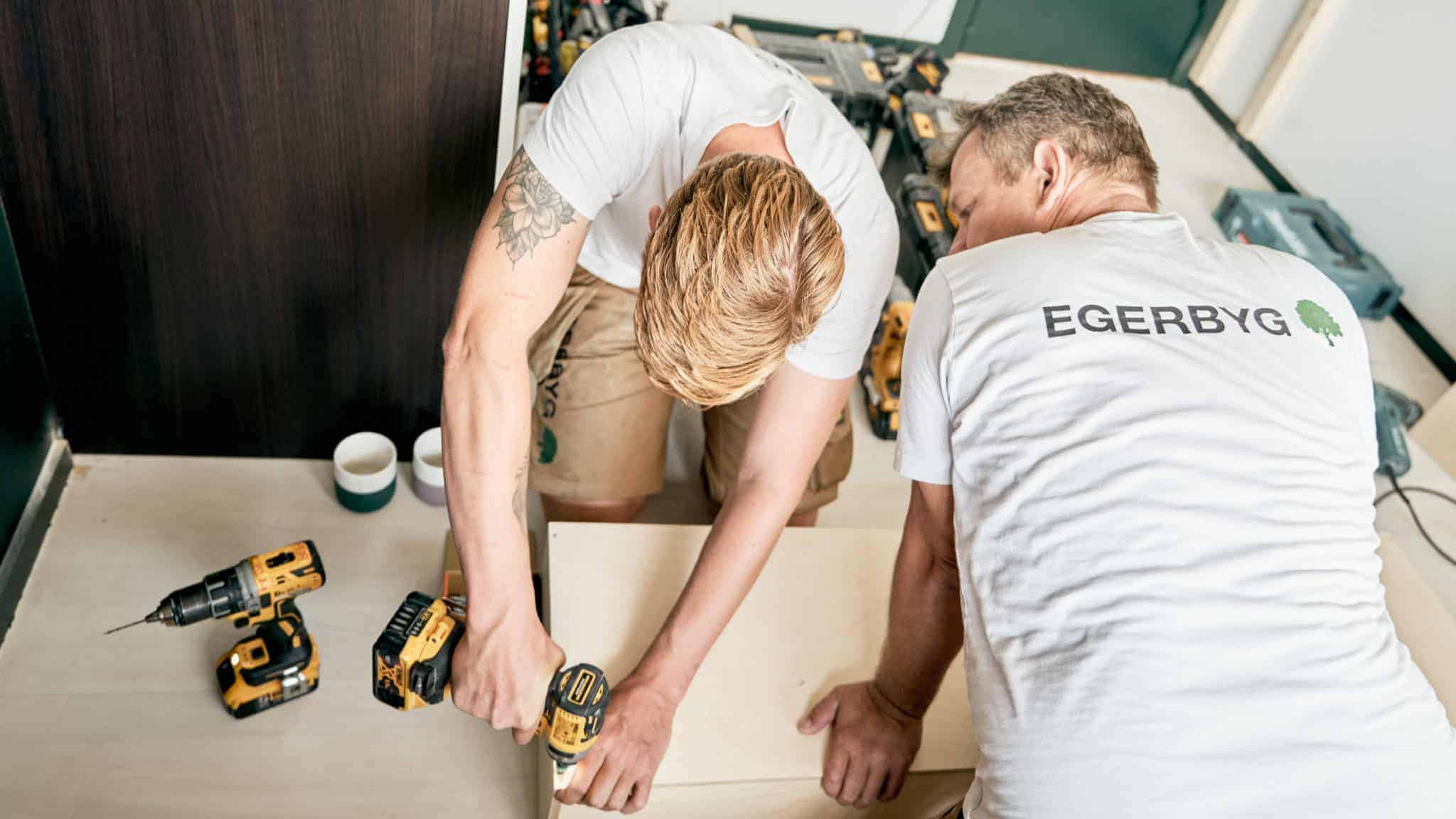 Egerbyg medarbejder skruer skruer i plade mens den anden holder