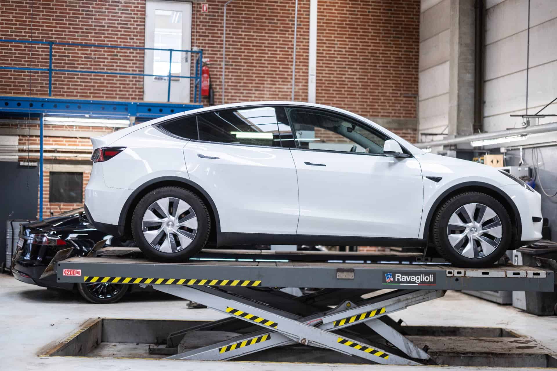 Hvid elbil hævet på lift til eftersyn på værkstedet