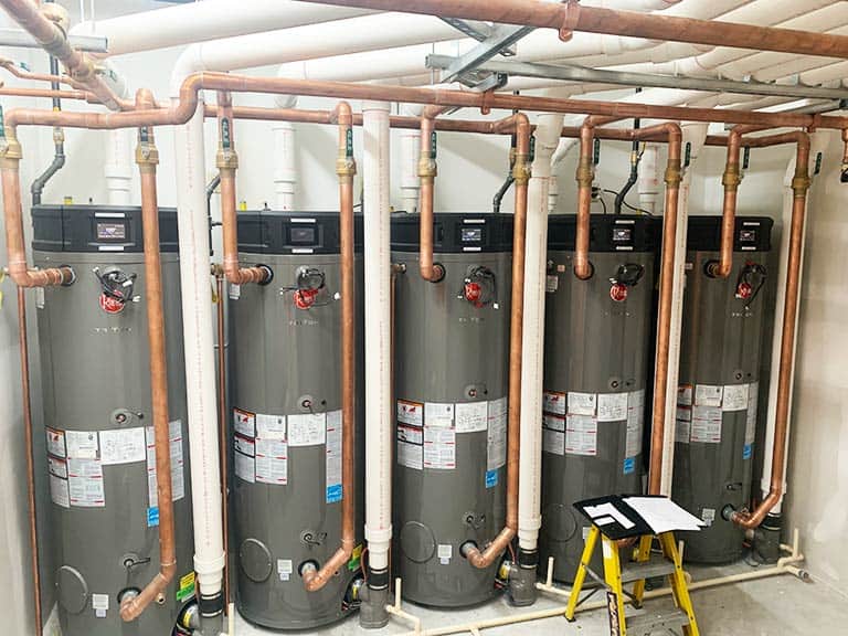 Five high efficiency water heaters are installed against the wall in a commercial building.