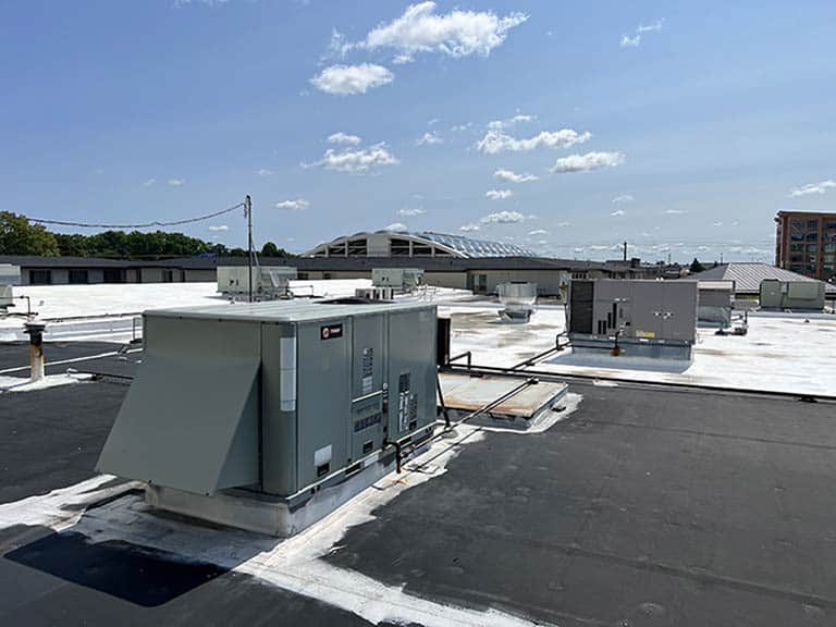 A large rooftop unit sits atop a building under a clear blue sky.