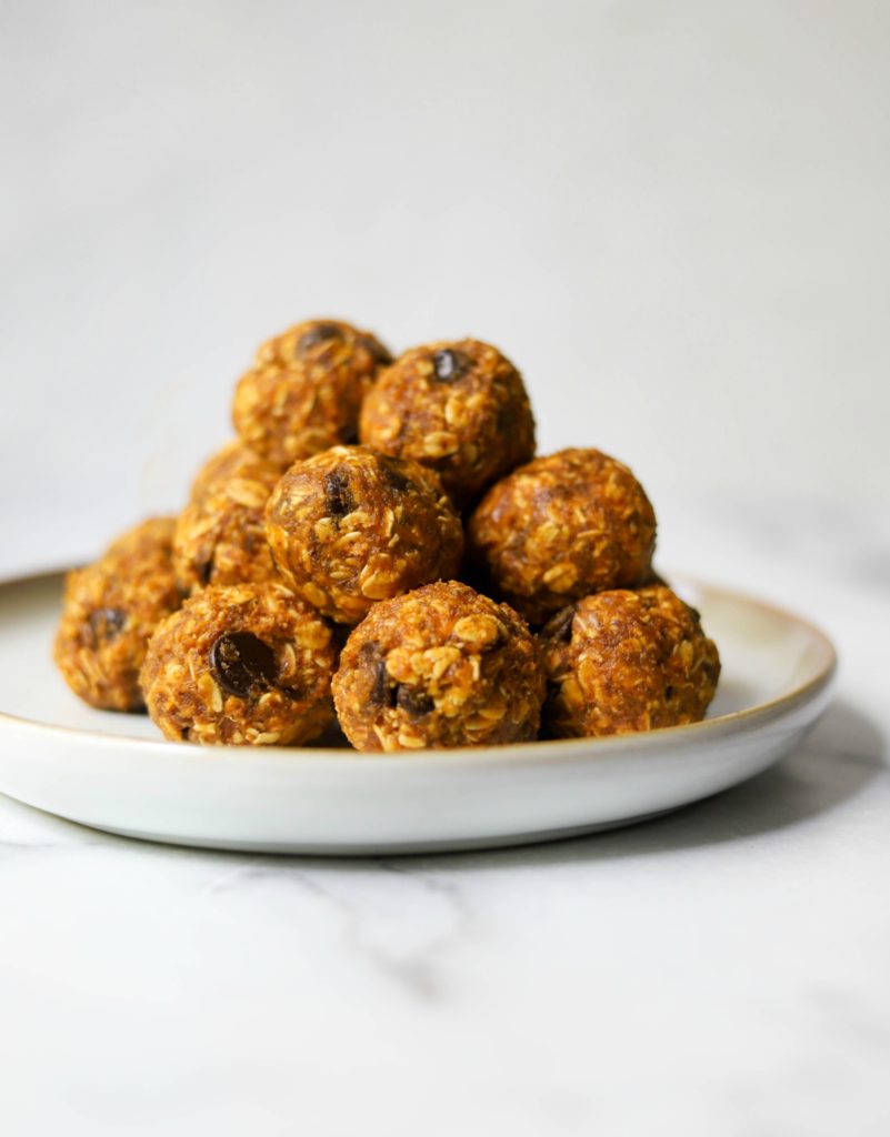 Stack of pumpkin cookie dough balls on a white plate