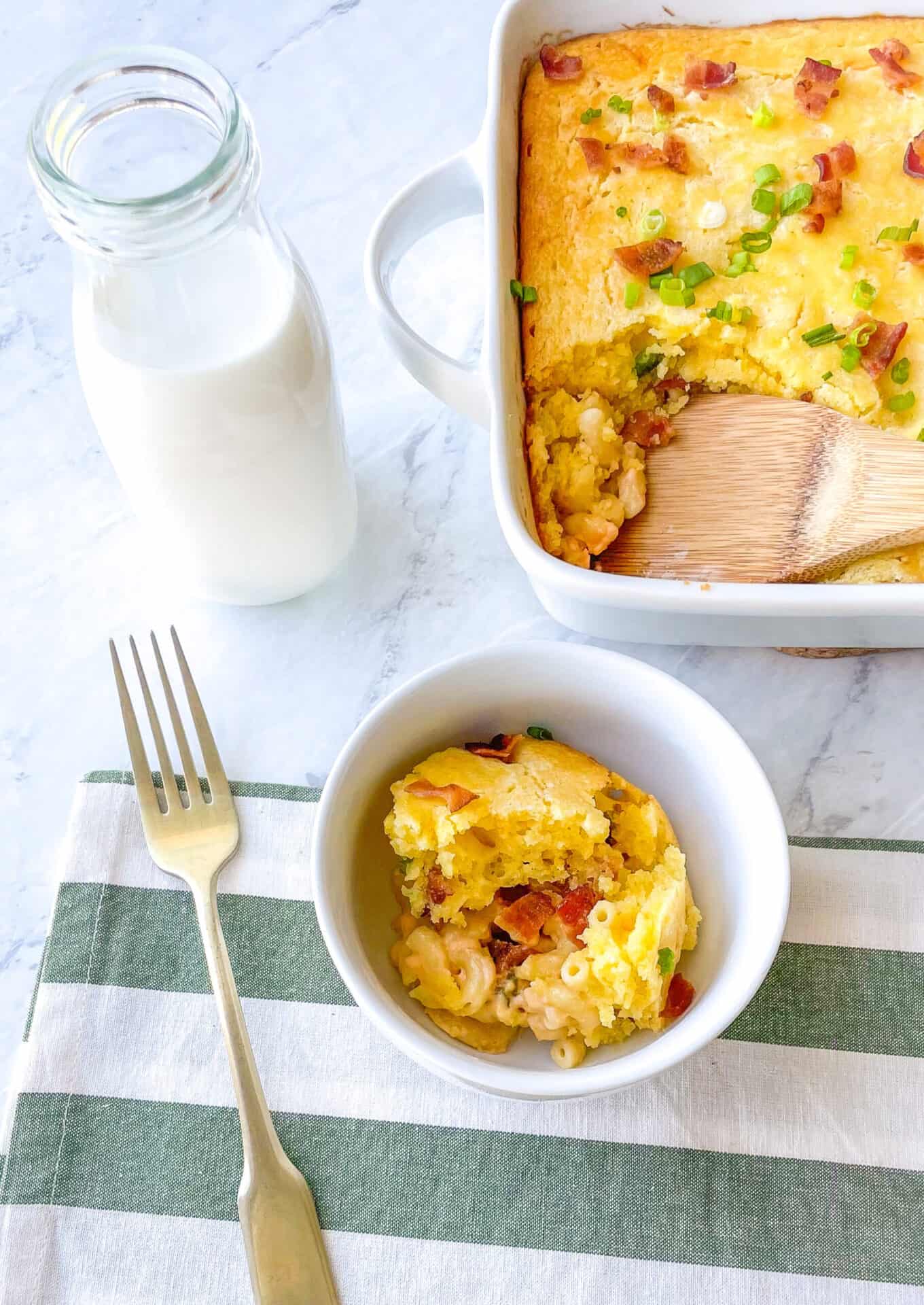bowl containing cornbread casserole with a glass of milk