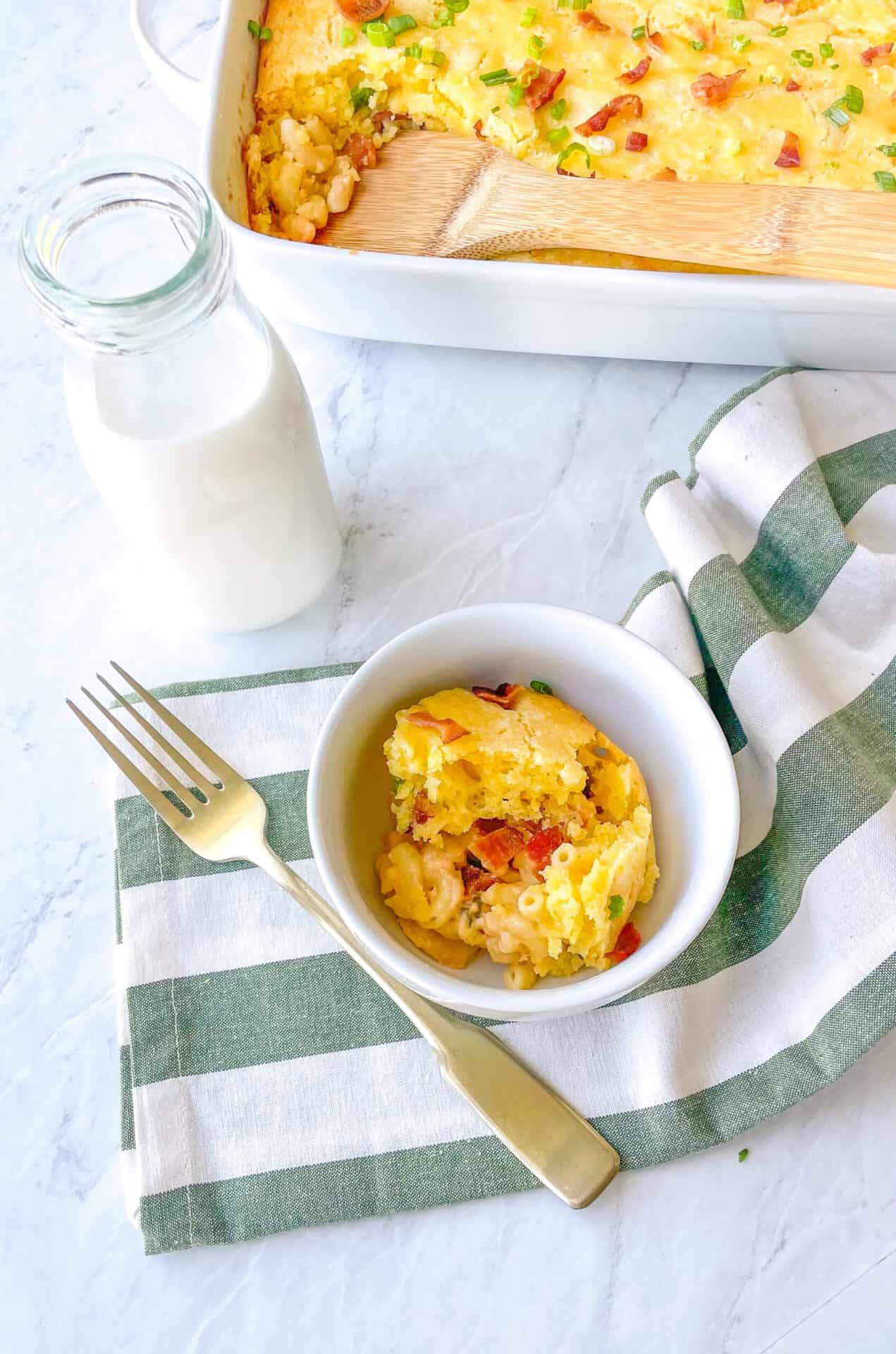 bowl containing cornbread casserole with a glass of milk