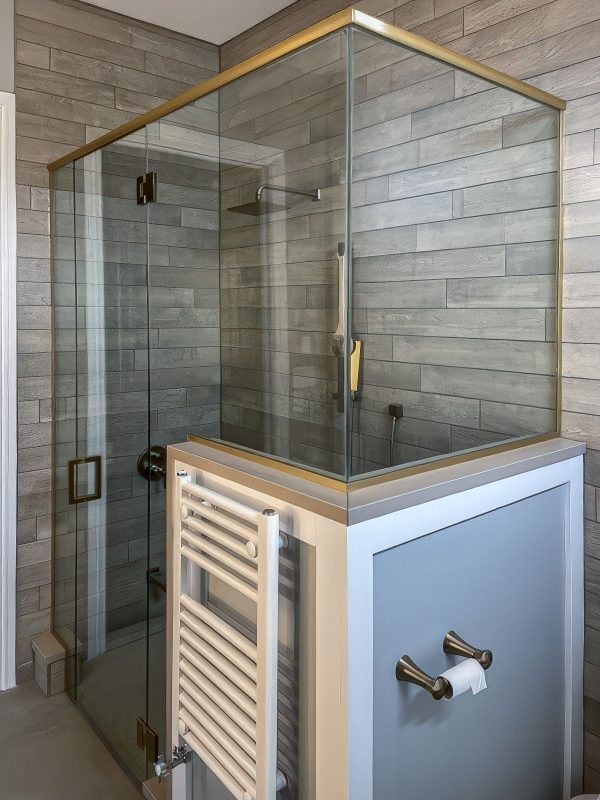 Shower glass enclosure with custom frameless design and gold trim for elegance and durability in Kingston Ontario. Perfectly tailored install blending modern style with practicality.