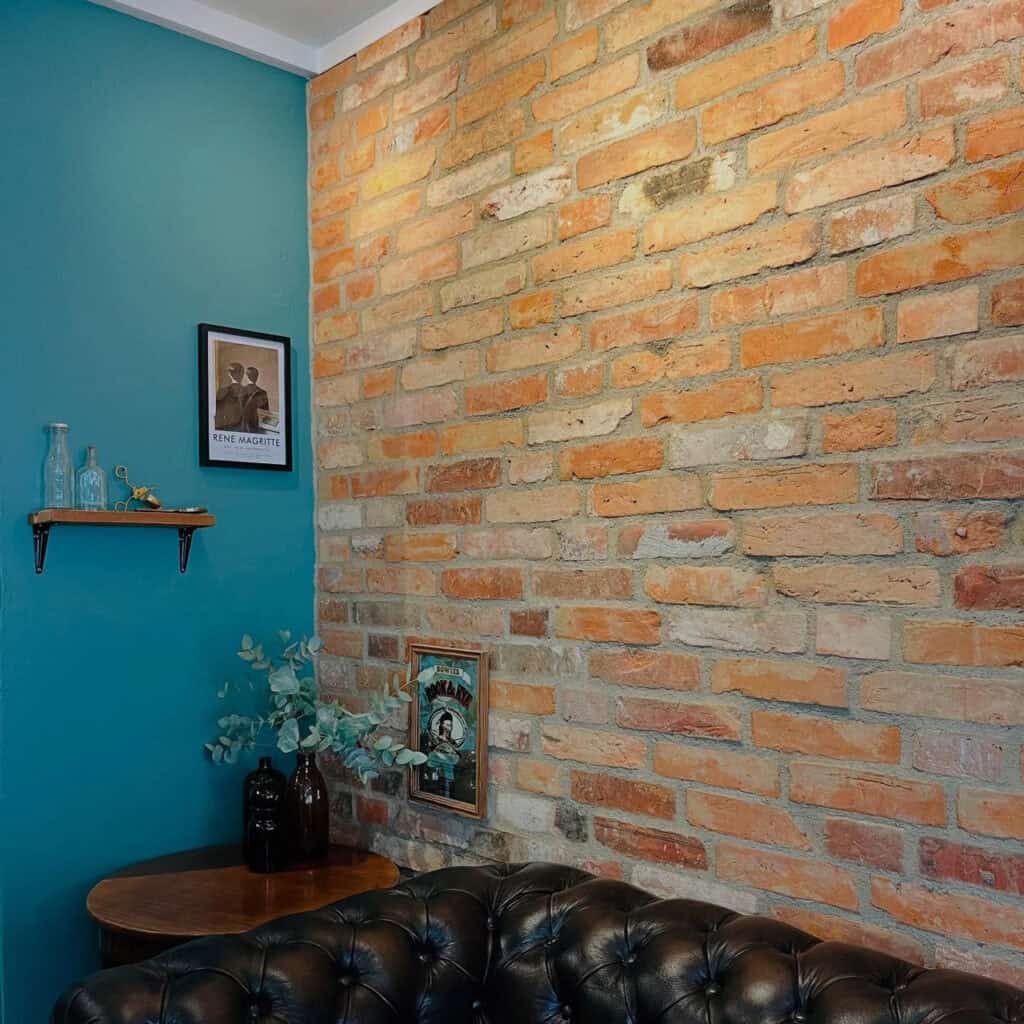 Indretning med murstensvæg og lædersofa hos The Barberhaus frisør i Bagsværd