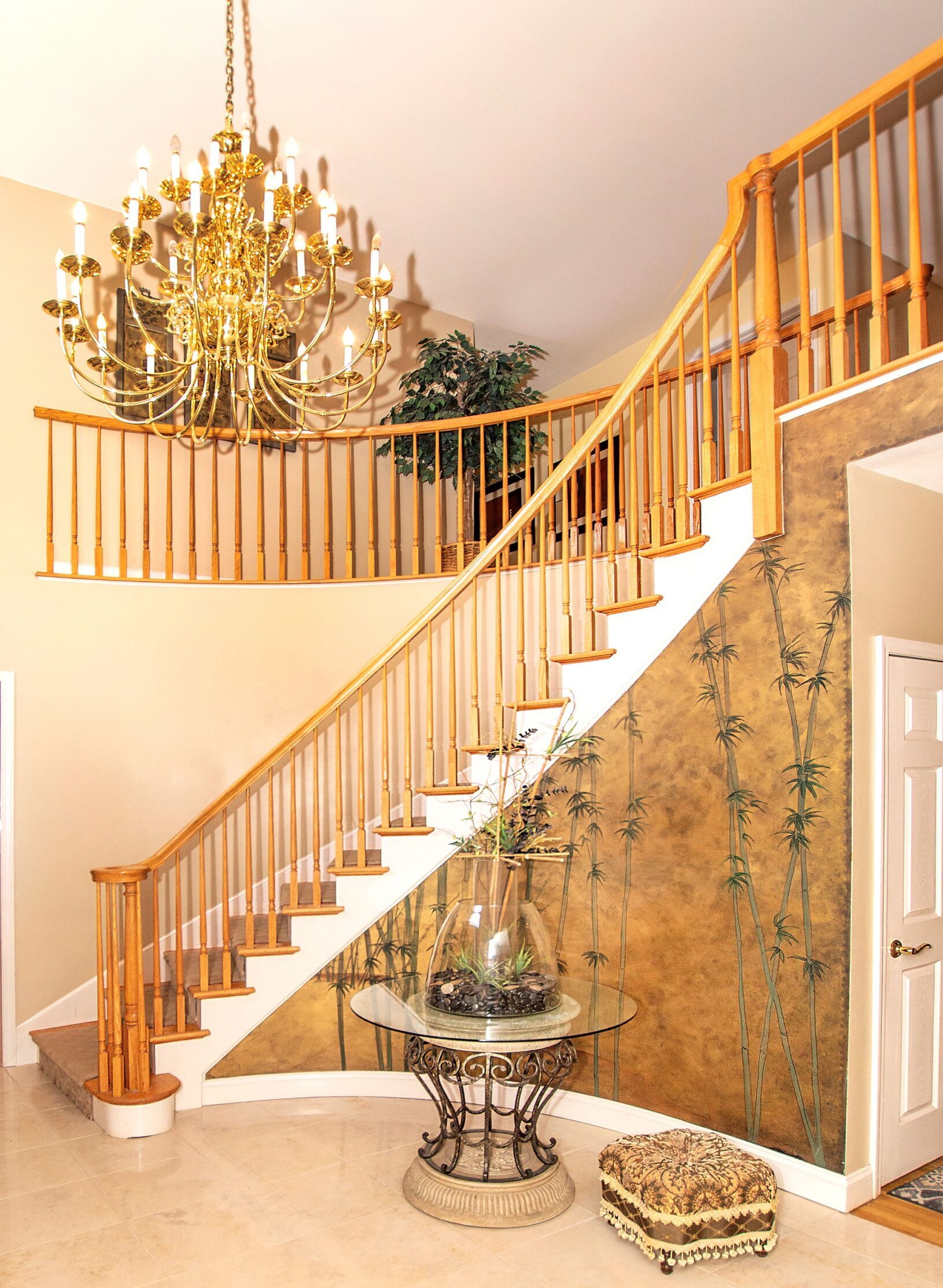 Foyer with elegant balcony, chandelier and curved staircase.