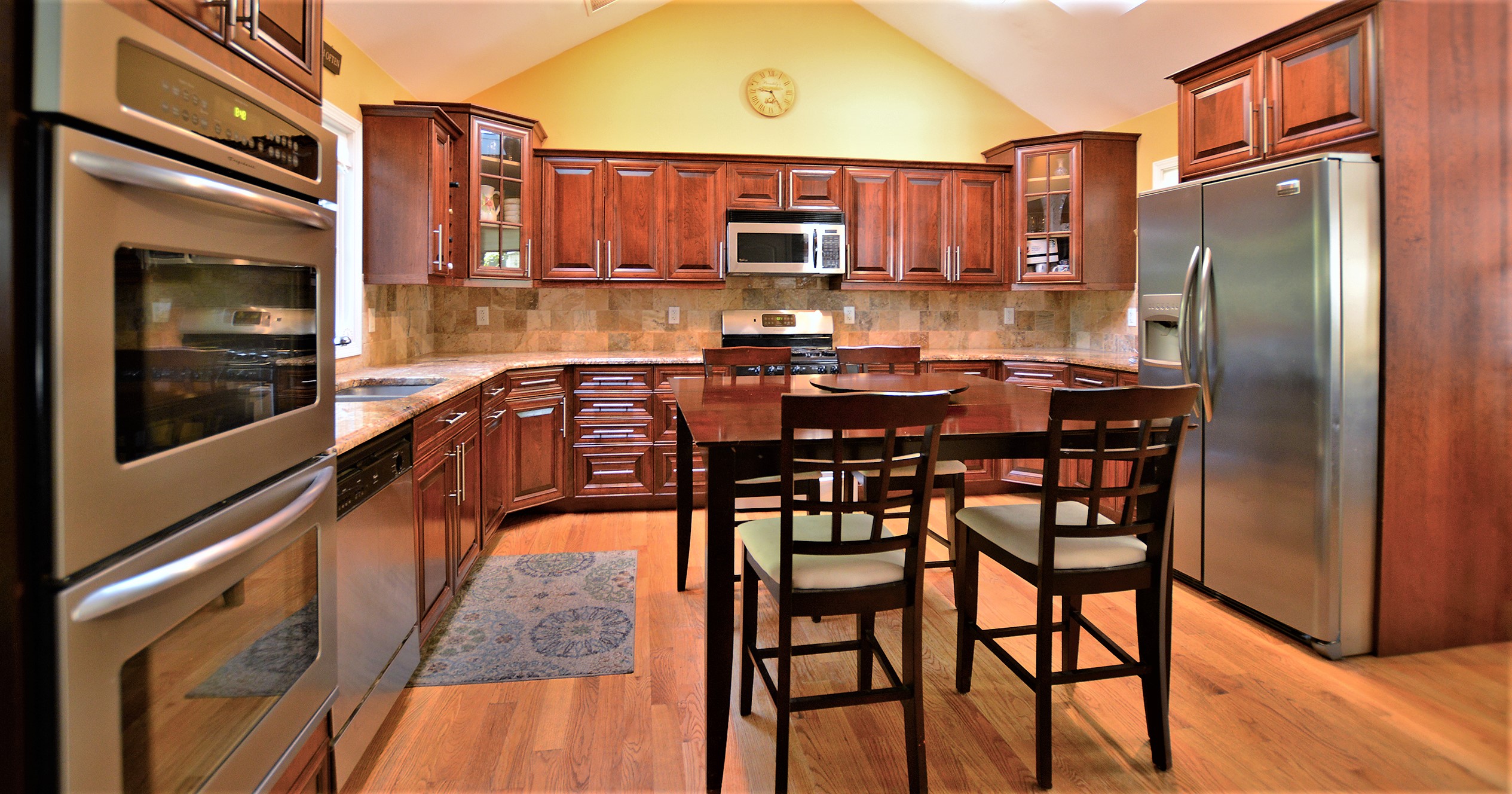 Eat-in kitchen with solid wood cabinetry and appliances on three sides.
