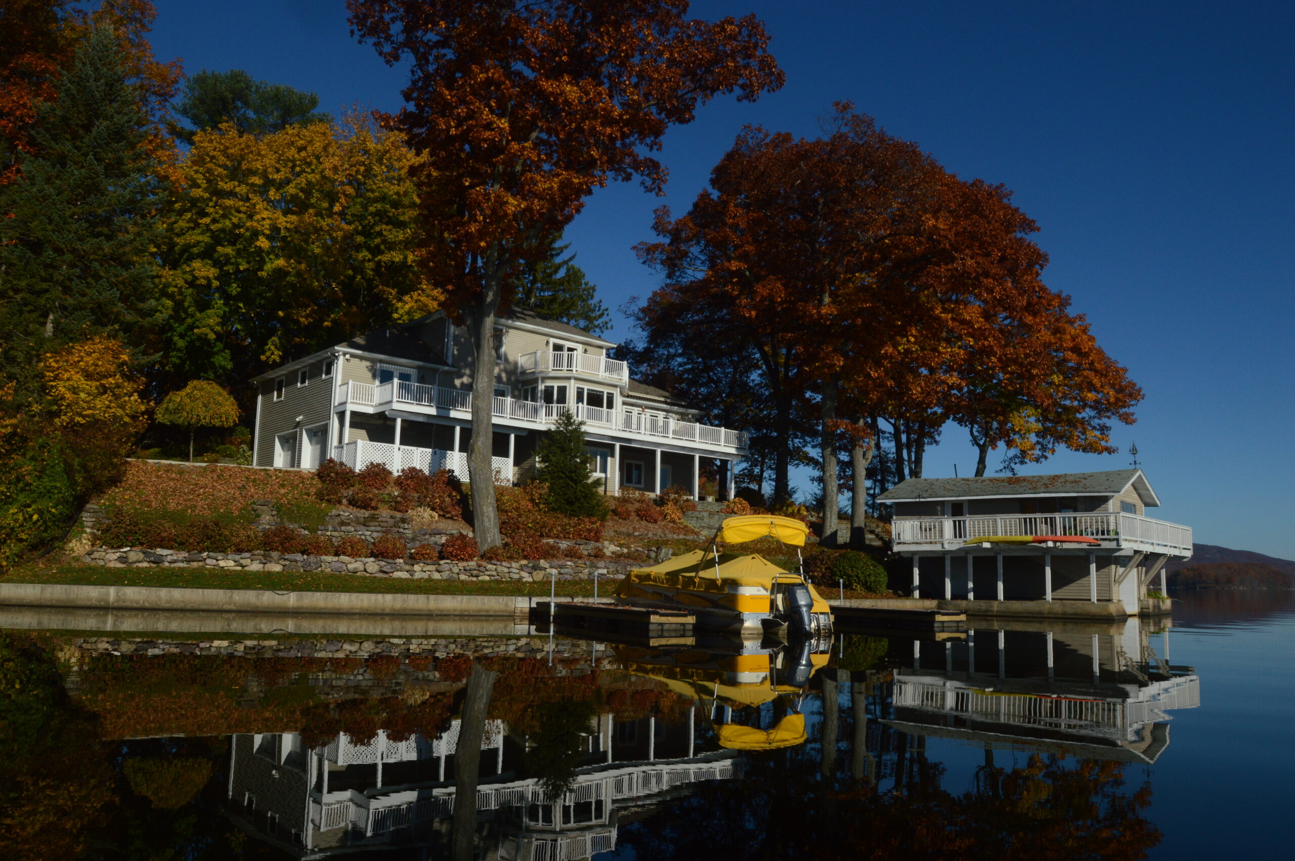Lakefront mansion with docks and boathouse photographed in autumn.