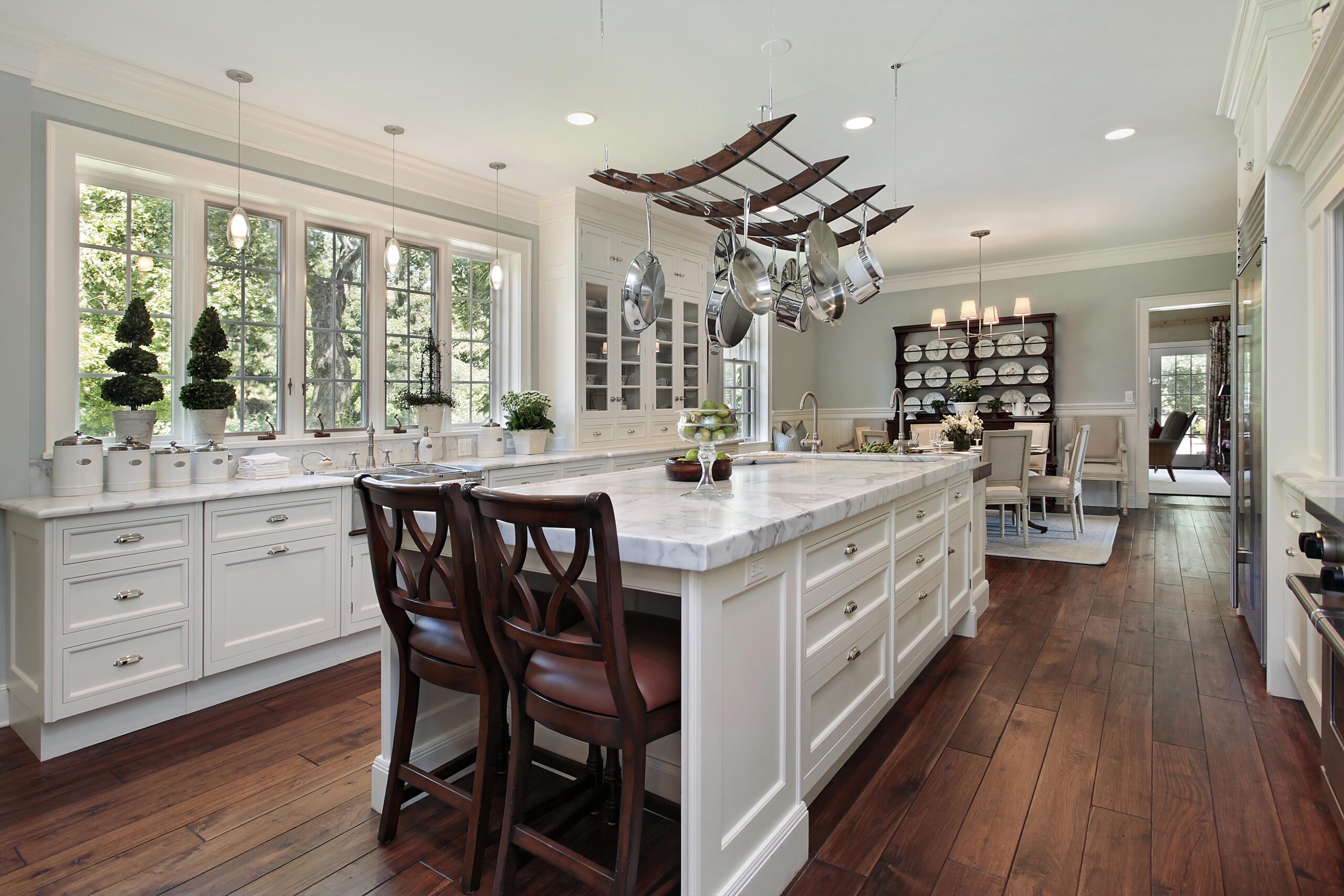 Large white gourmet kitchen with granite center island and overhead rack.