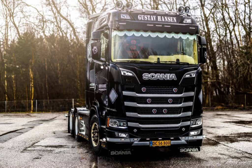 Fronten på en sort Scania lastbil - "GUSTAV HANSEN"