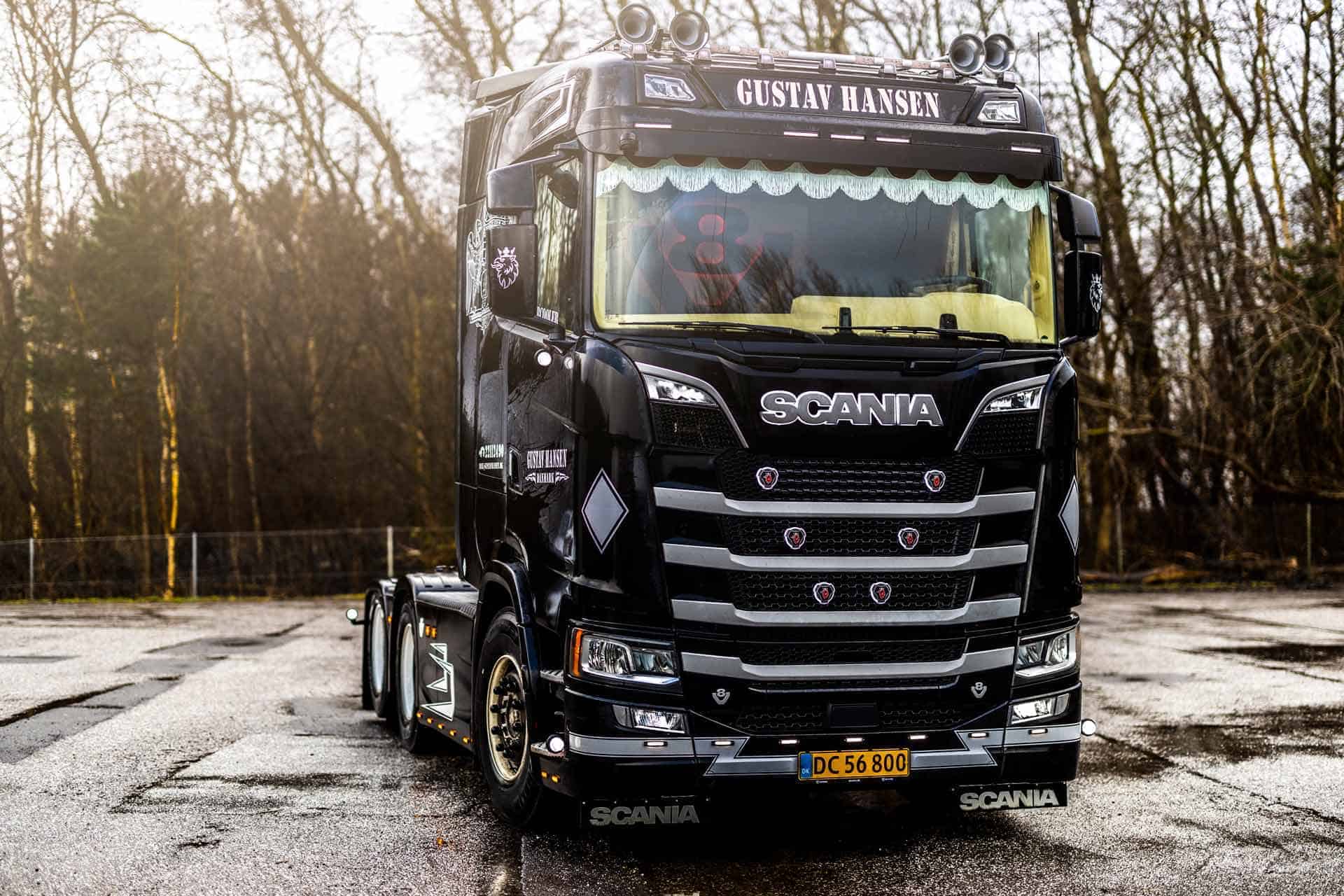 Fronten på en sort Scania lastbil - "GUSTAV HANSEN"