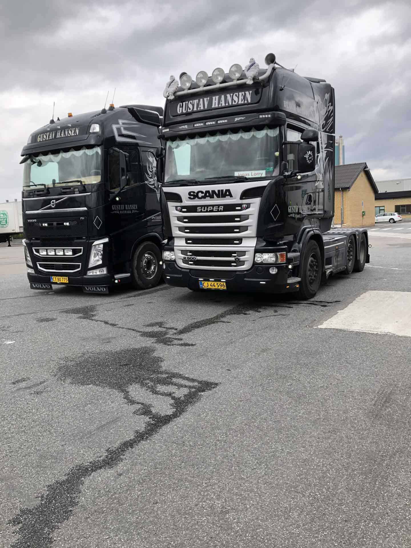 To sorte Scania lastbiler fra vognmandsfirmaet parkeret tæt ved siden af hinanden.