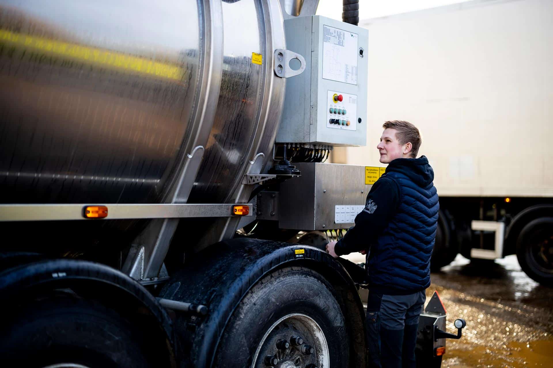 Chauffør inspicerer siden på en blank tanktrailer fra vognmand Gustav Hansen.